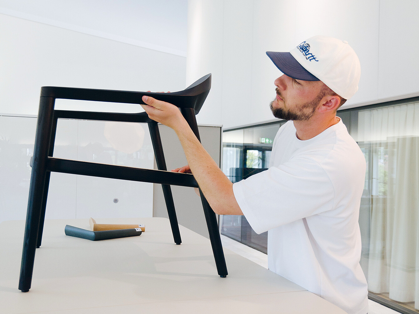 Designer Konstantin Thomas examining the black wooden se:café chair, highlighting its durable and comfortable craftsmanship.