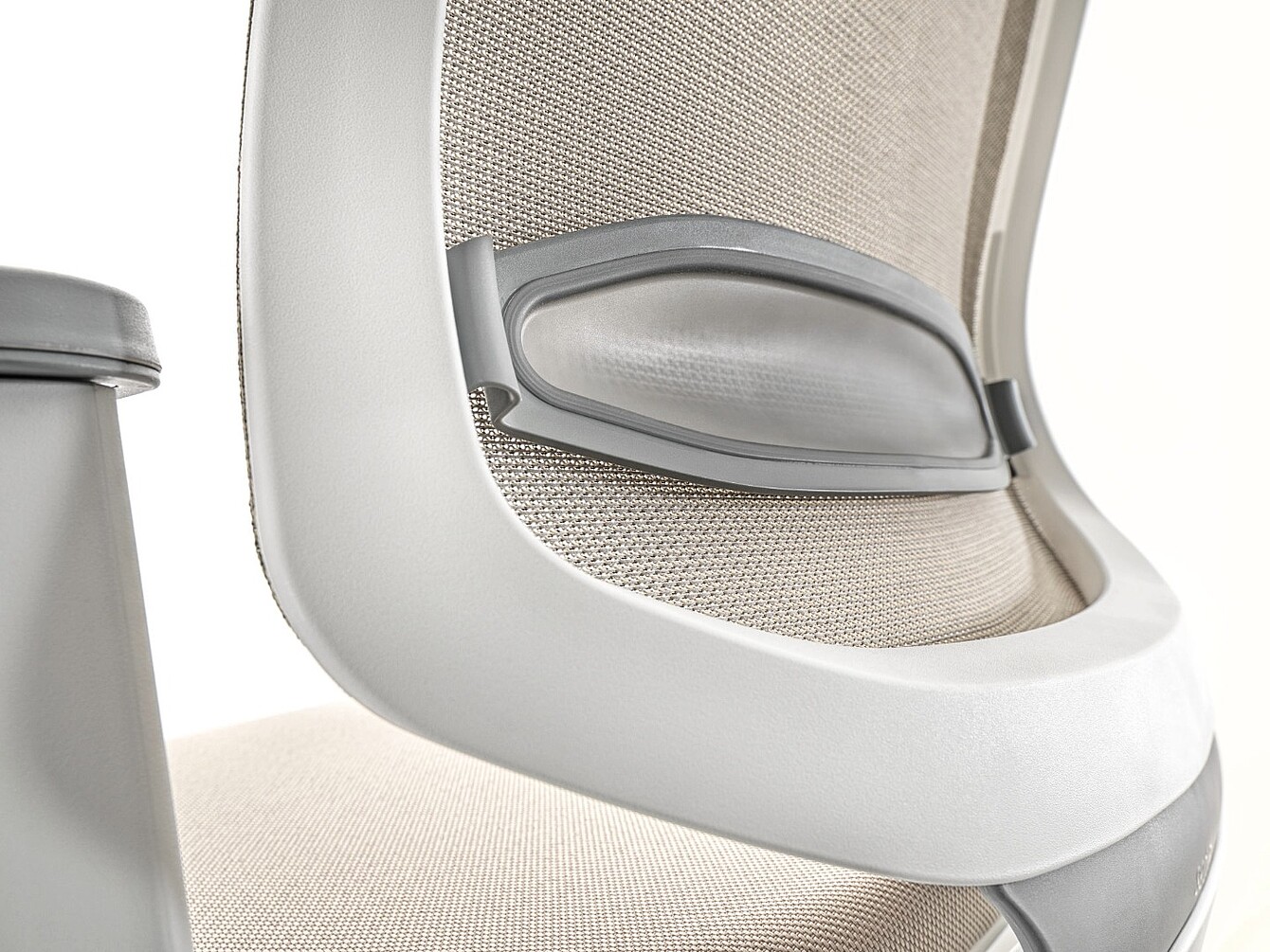 Close-up of a beige mesh office chair backrest with integrated adjustable lumbar support and a gray armrest