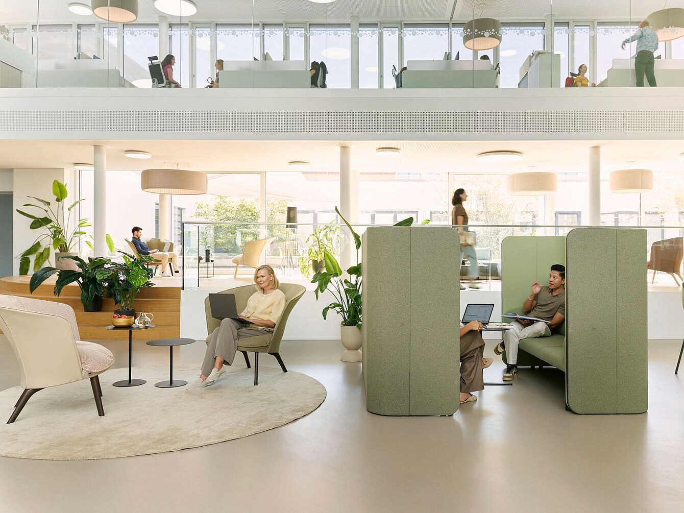 Modernes Büro mit offenen Arbeitsbereichen, Sitznischen mit hohen Trennwänden und Pflanzen zur Verbesserung der Raumakustik