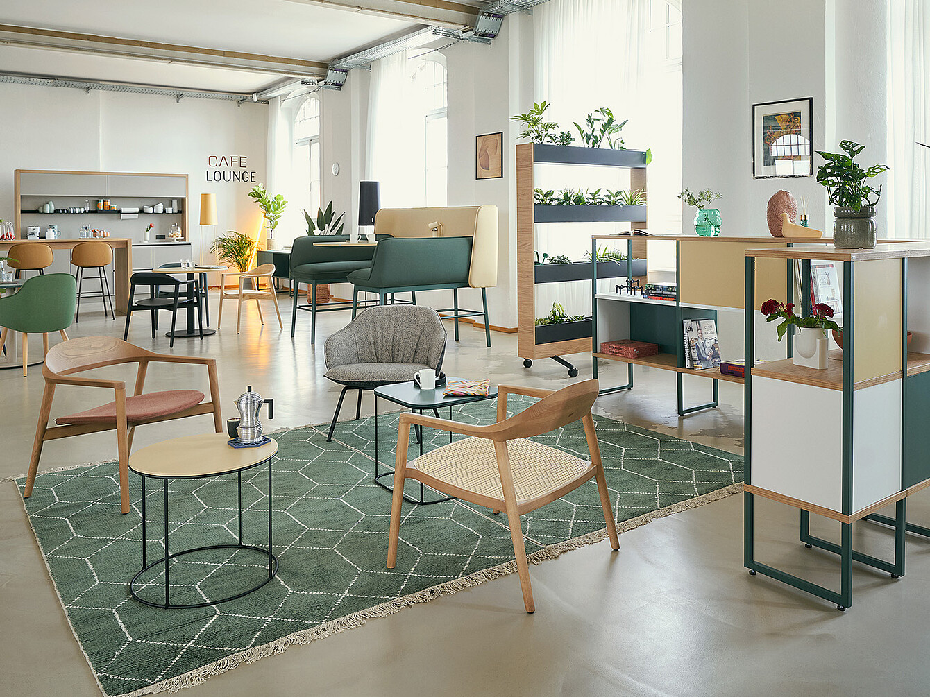 Modern Smart Café in an office with lounge seating, green rug, wooden tables, plants, and a café lounge area blending work and relaxation spaces