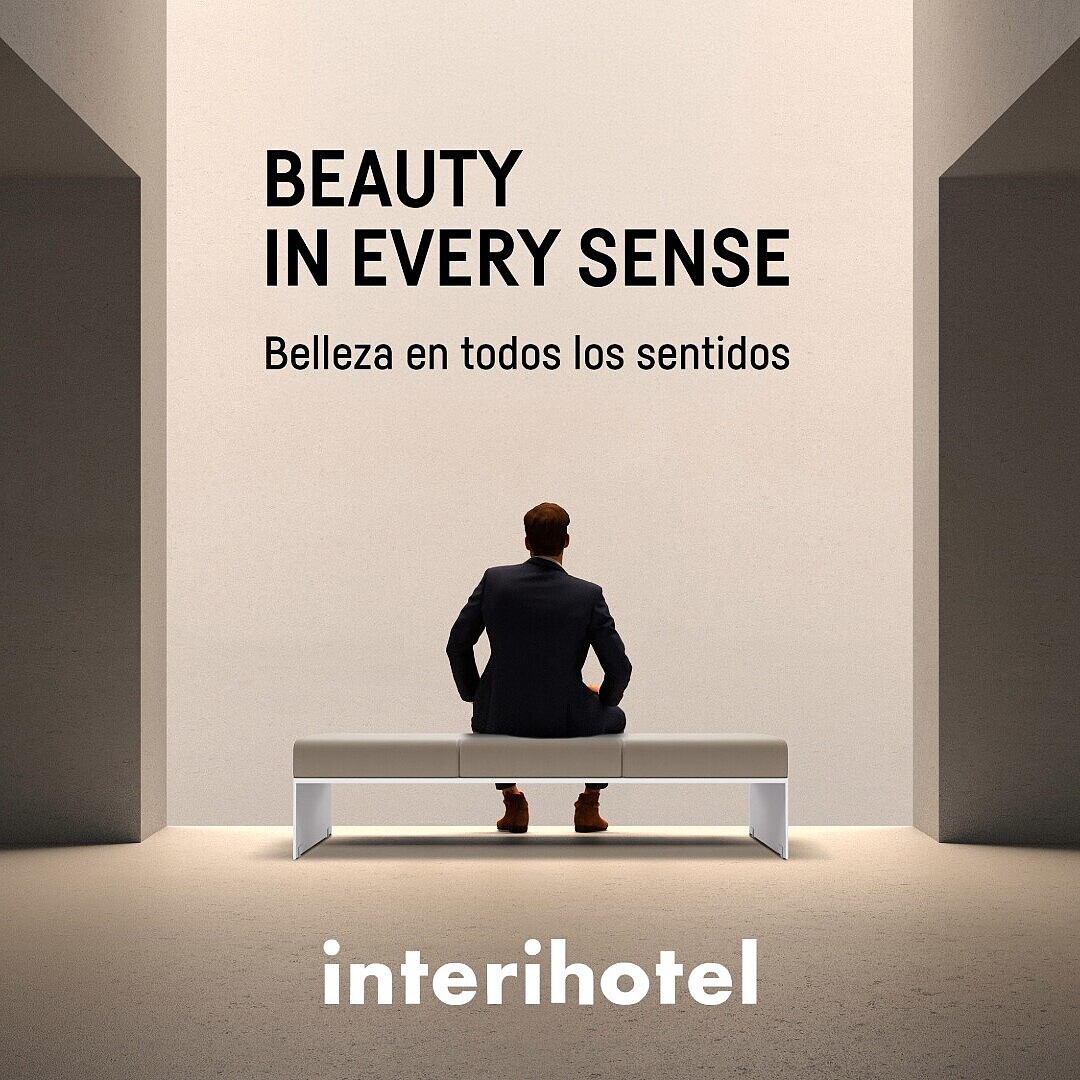 Ein Mann sitzt auf einer weißen Bank vor einer hellen Wand mit den Schriftzügen 'BEAUTY IN EVERY SENSE', 'Belleza en todos los sentidos', 'interihotel', 'Caimi', 'sedus', '17-19 Nov' und 'IFEMA Madrid 2026'.