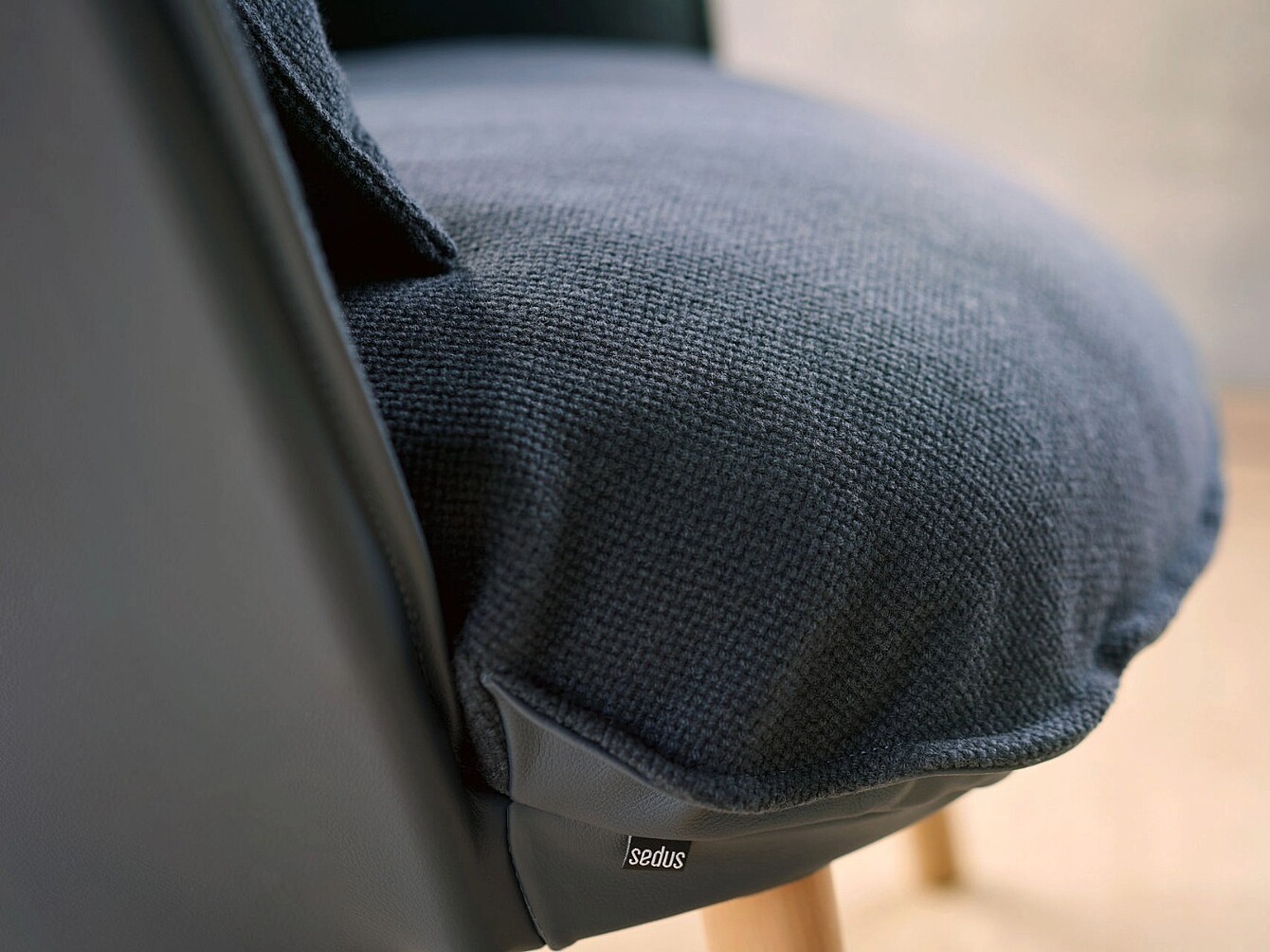 Close-up of a se:cove chair seat with textured upholstery and a small fabric tag showing the Sedus brand