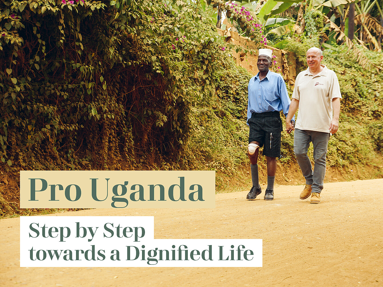 Zwei Männer gehen auf einem Weg entlang, einer trägt eine Prothese am linken Bein, umgeben von dichtem Grün.