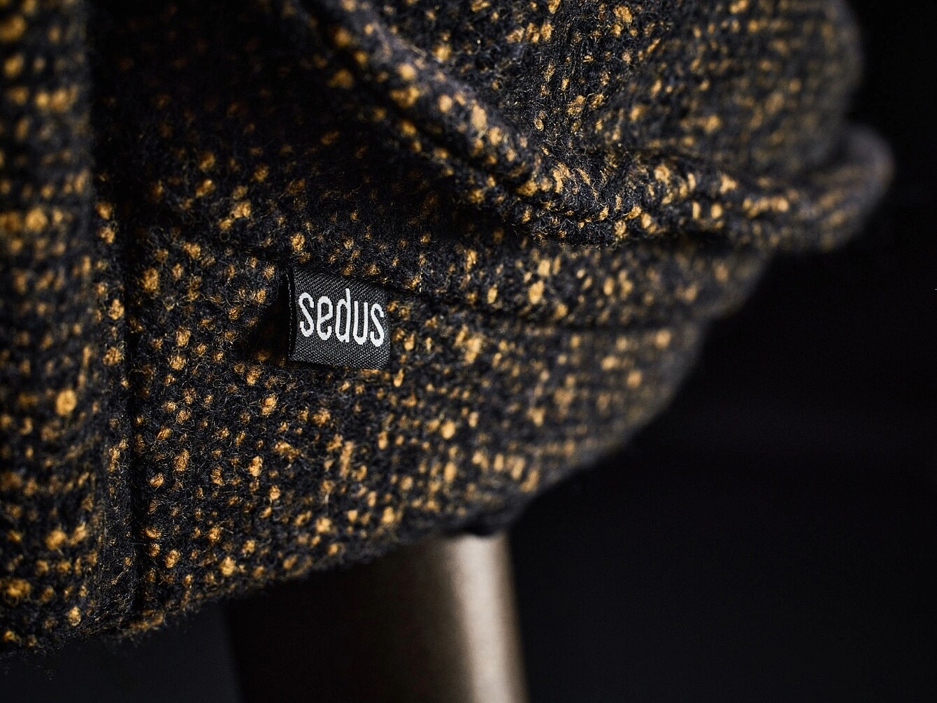 Close-up of a fabric upholstery with a small black label reading 'sedus' in white