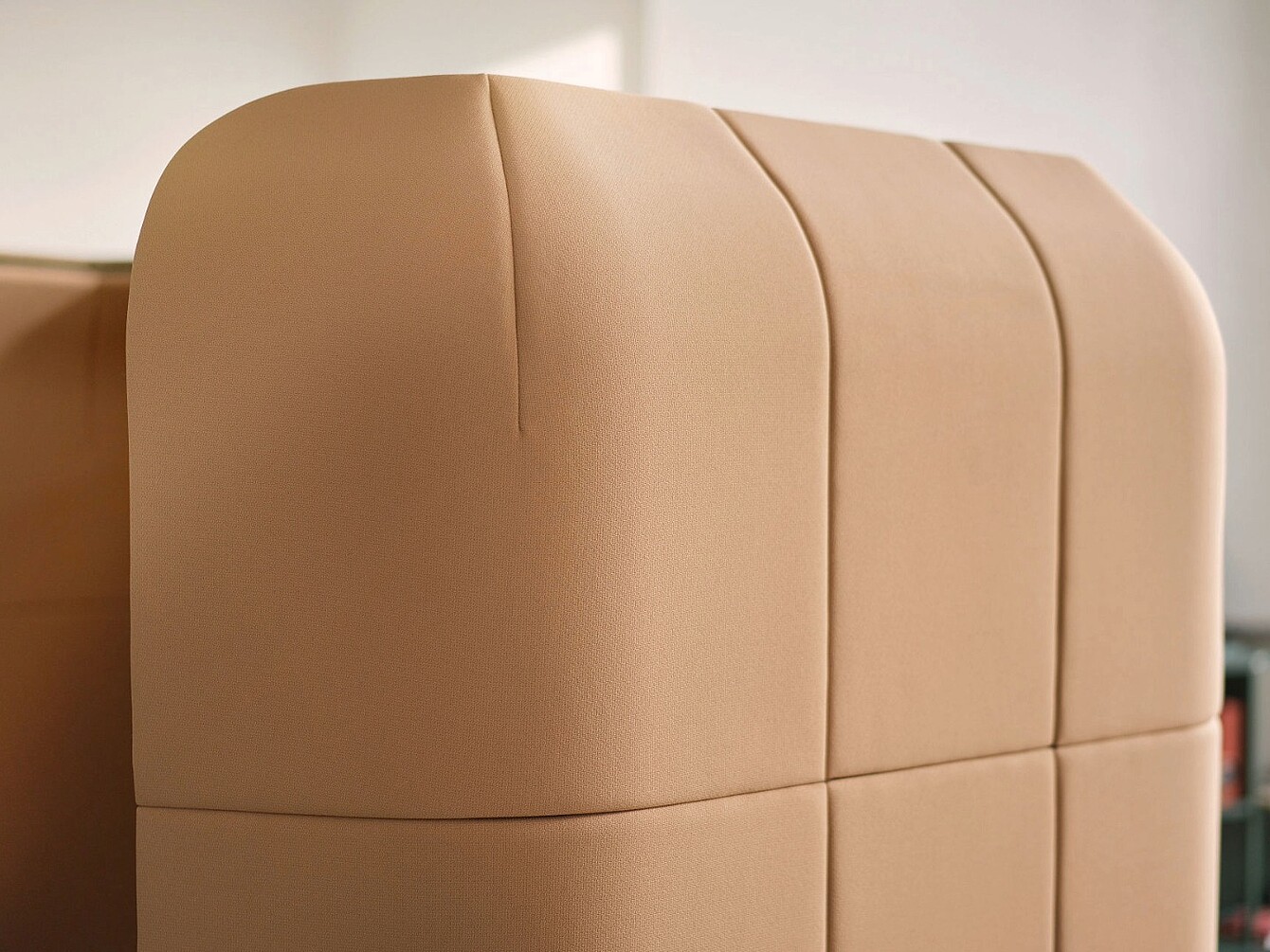 Nahaufnahme eines gepolsterten, beige-farbenen Trennelements mit vertikalen Nähten als Teil der se:hive Raumlösung von Sedus