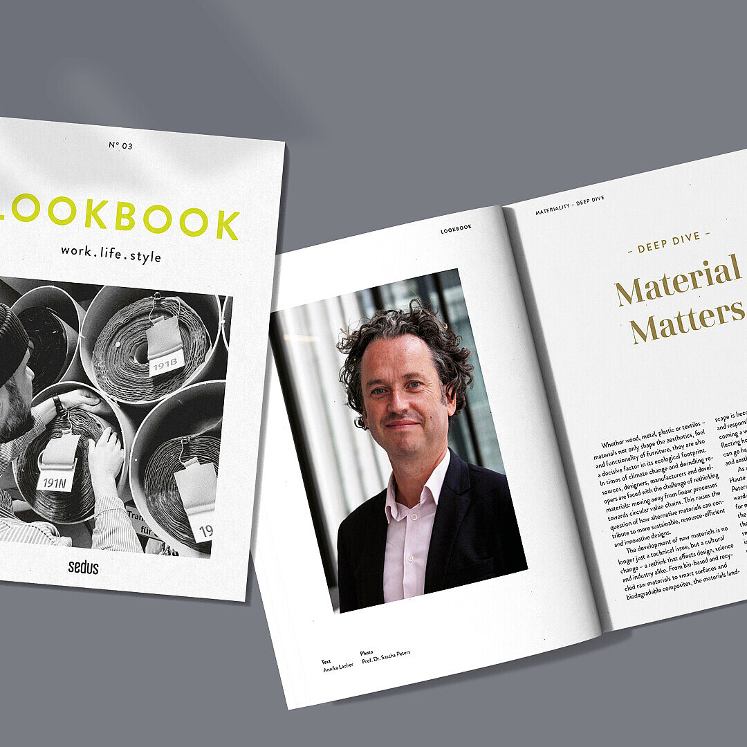 A magazine titled 'LOOKBOOK work.life.style' with a black-and-white photo on the cover and an open spread showing a portrait on the left page and an article titled 'Material Matters' on the right page.
