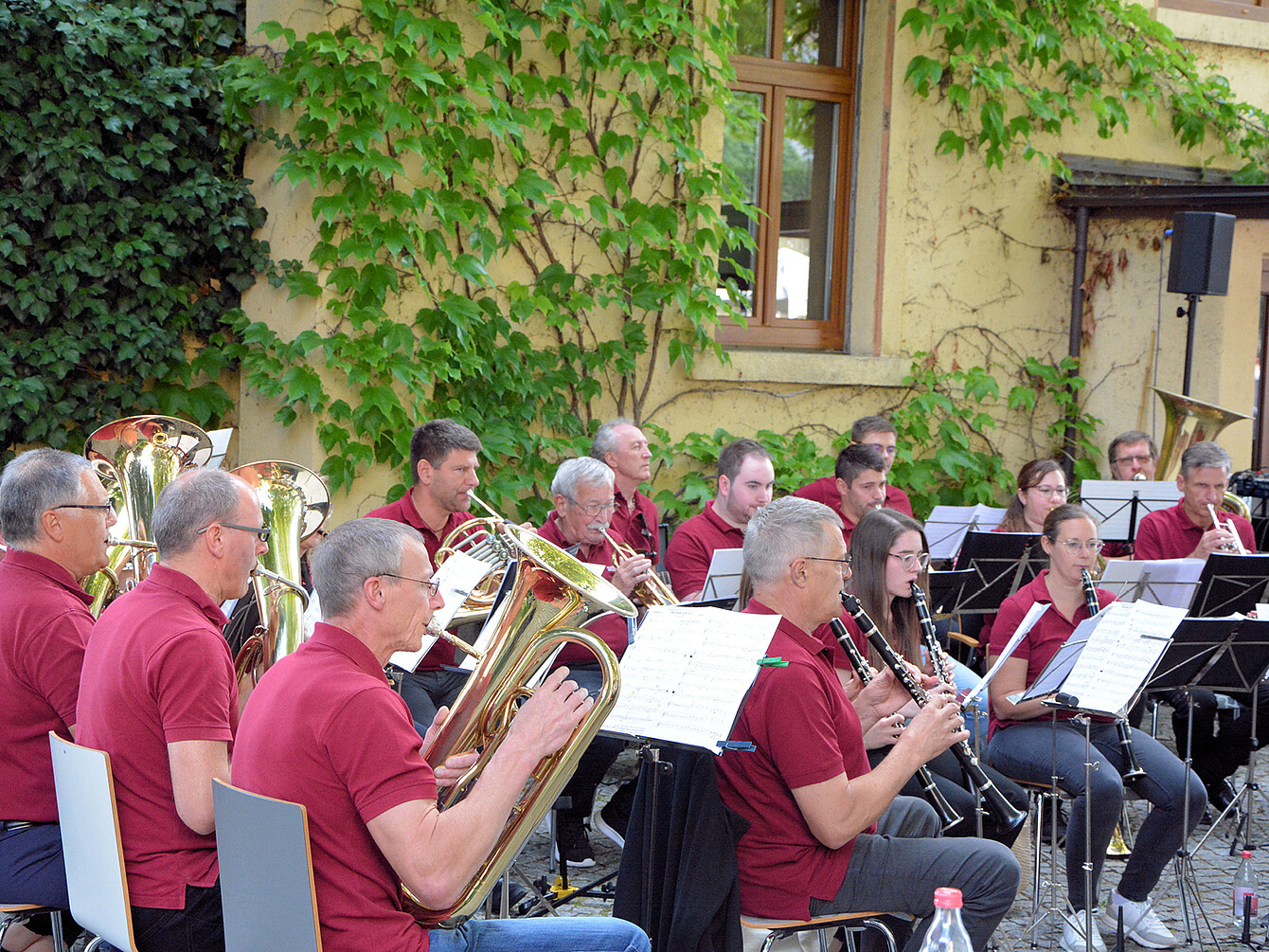 Sedus Werksmusik spielt bei Jubiläumskonzert im Freien, Musiker in roten Poloshirts mit Blech- und Holzblasinstrumenten