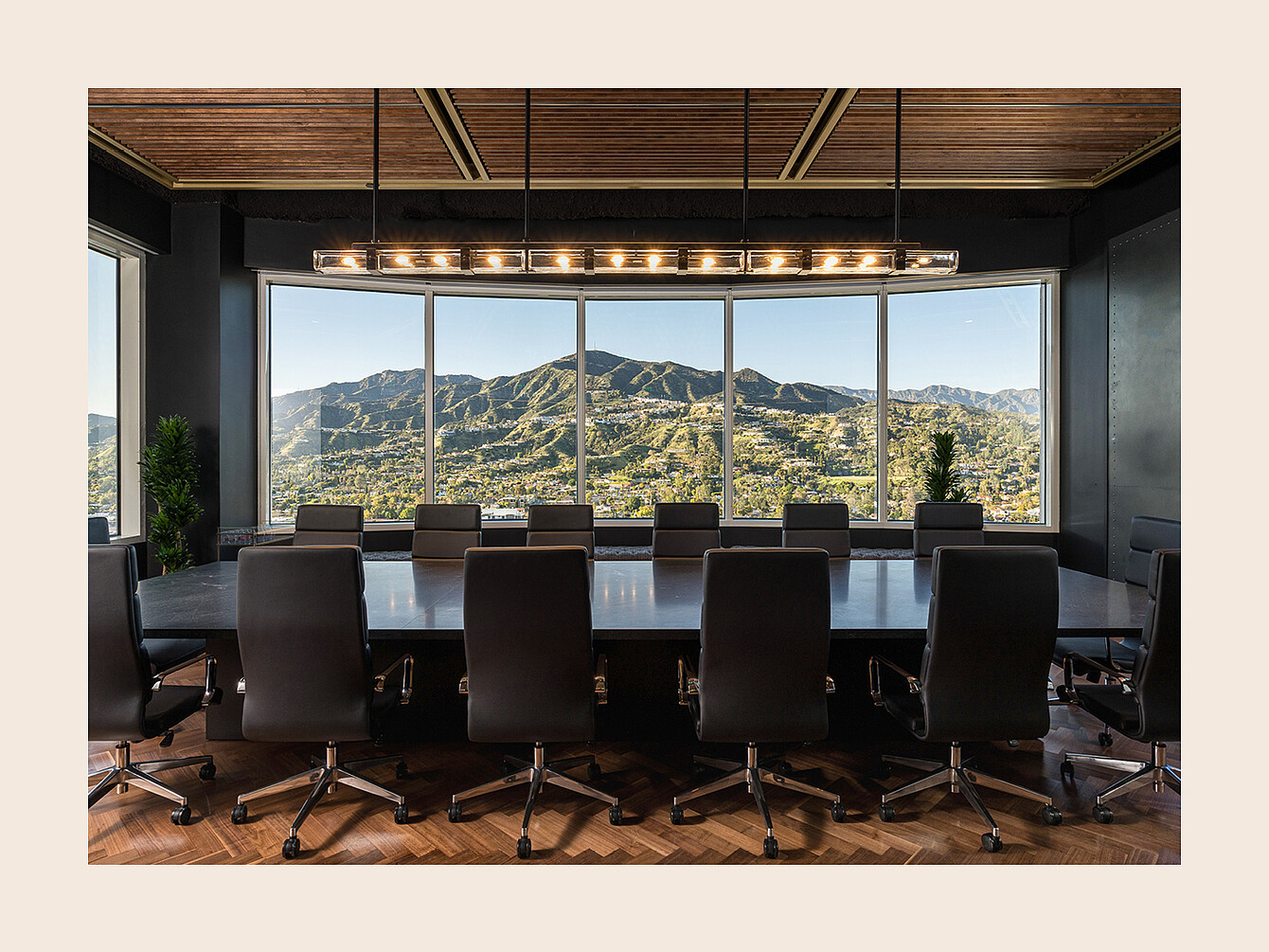 Conference room with a long table surrounded by office chairs facing large windows showing a mountain landscape