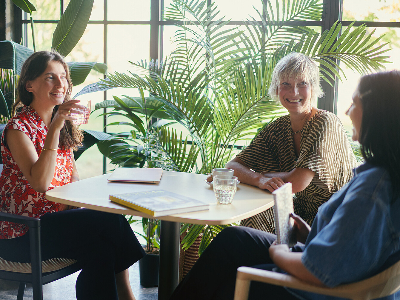 Three women have a lively conversation in the office